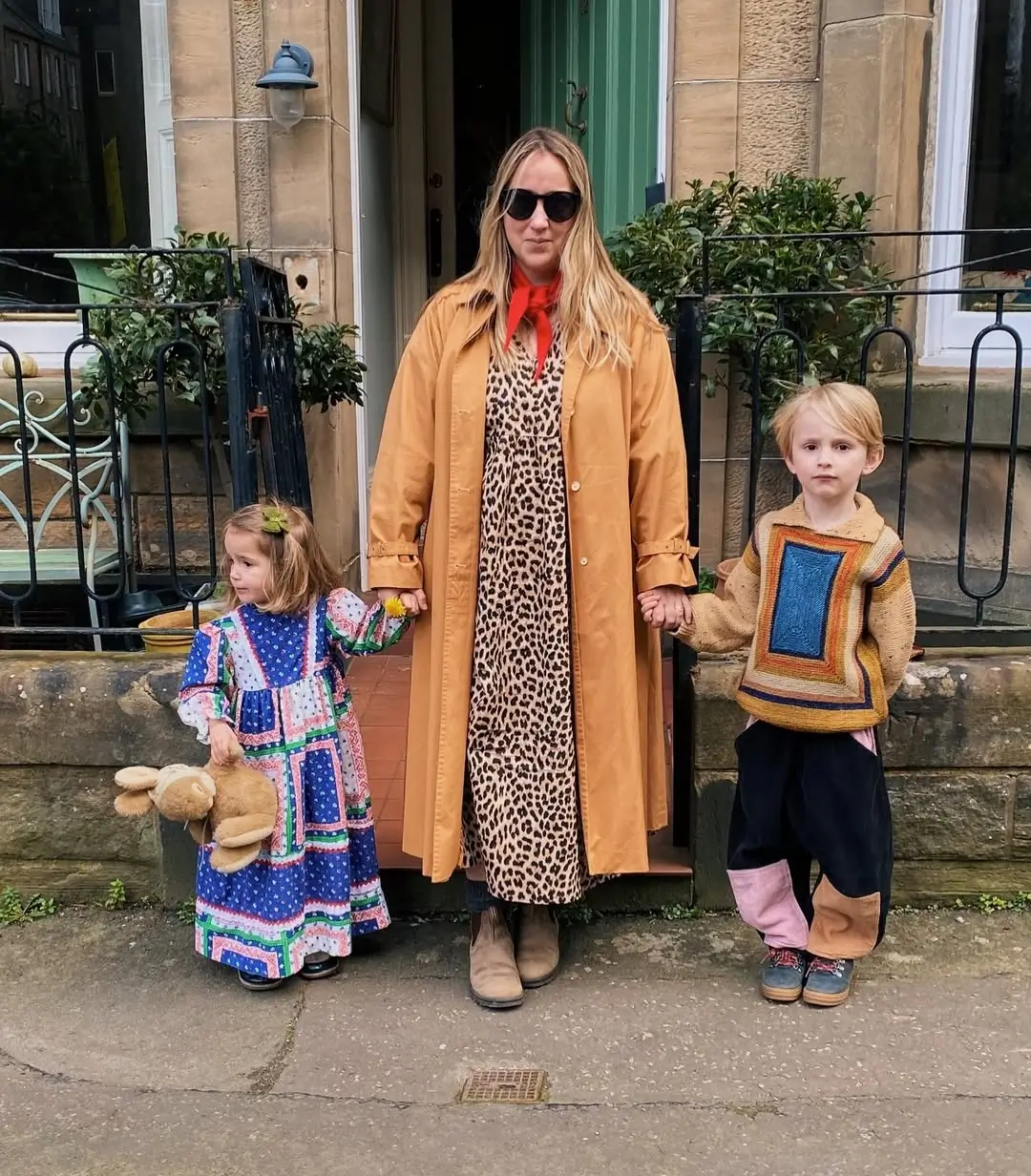 mãe e duas crianças um rapaz e uma rapariga vestidos de forma cool com cores e padrões e um peluche de coelho na mão